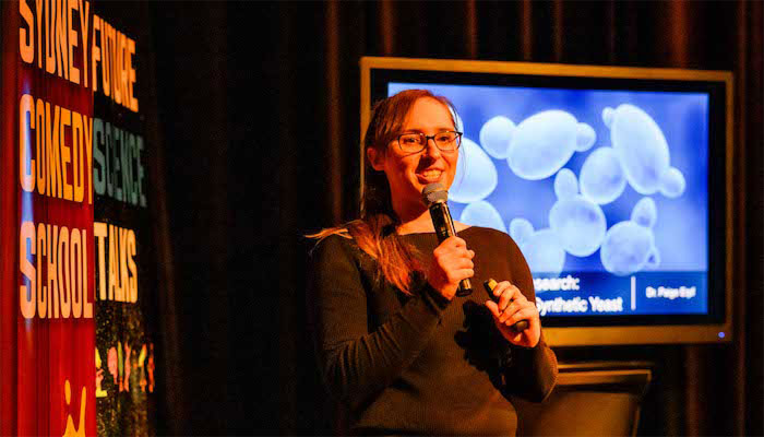Scientist Paige Erpf on stage doing stand up comedy.