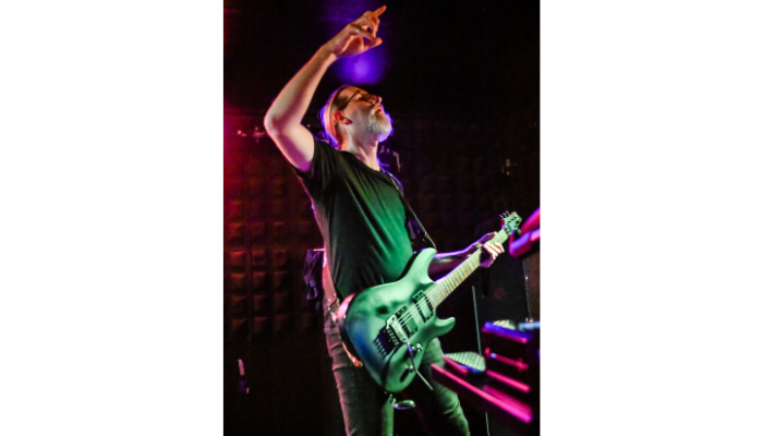 Steve Collins holding playing his guitar on stage