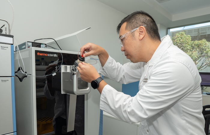 Associate Professor Albert Lee loads a sample into a mass spectrometer