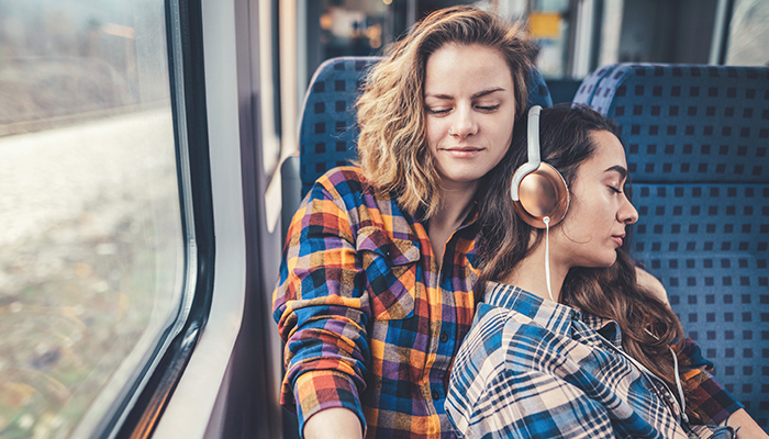 Female couple listening to music on a train