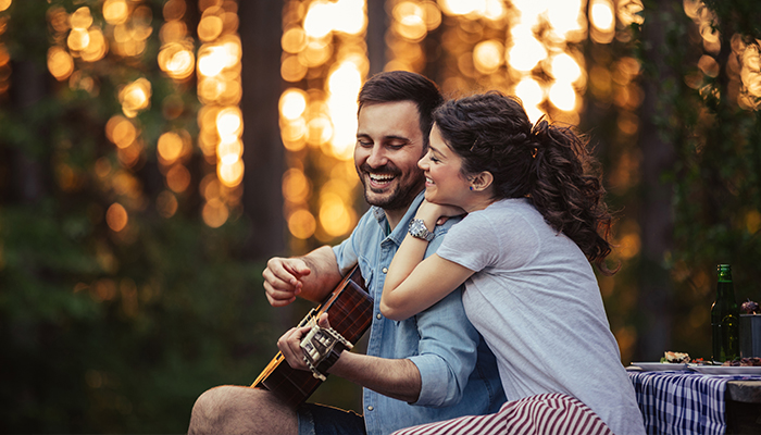 Man playing guitar to girlfriend