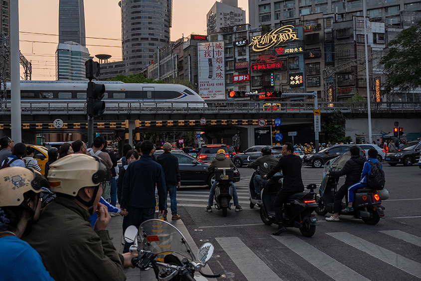 Pedestrians and motorcyclists waits to cross a intersection at a shopping district on April 03, 2025 in Shenzhen, China. China is facing unprecedented economic pressure following President Trump's "Liberation Day" announcement, which imposes a 54% tariff on nearly all Chinese imports to the U.S., effectively doubling existing levies.