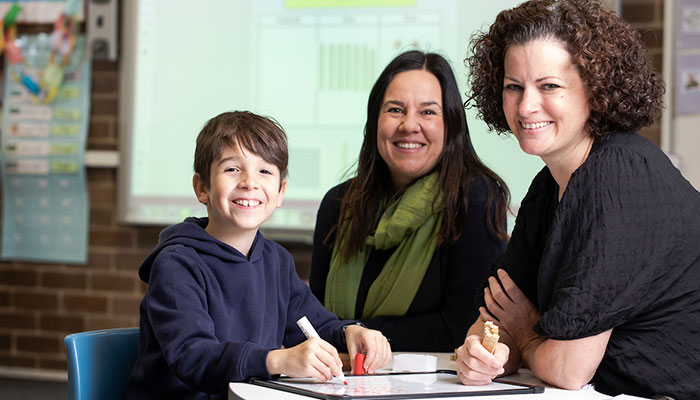 Dr Sarah Mills teaches young Jayden at Macquarie University's MUSEC school while mother Kerry watches on.